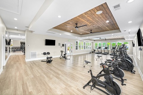 A gym with a row of stationary bikes and a television.