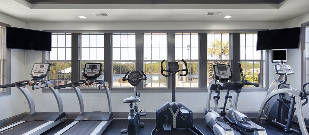 a gym with various workout machines in front of windows