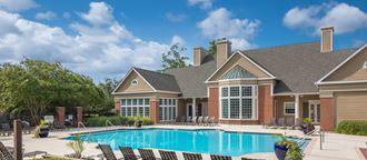 a large swimming pool in front of a house with chairs
