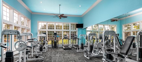 a gym with cardio machines and a ceiling fan