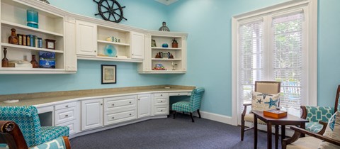 a home office with blue walls and white cabinets