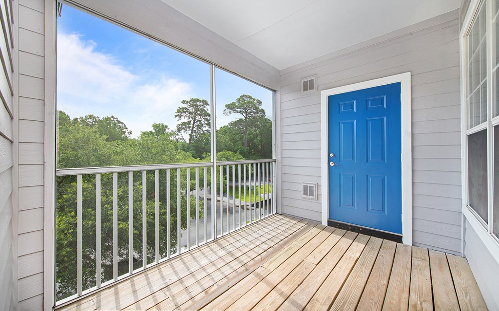 a blue door on a balcony with a view of trees