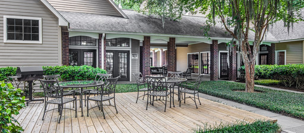 a patio with tables and chairs in front of a house