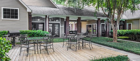 a patio with tables and chairs in front of a house