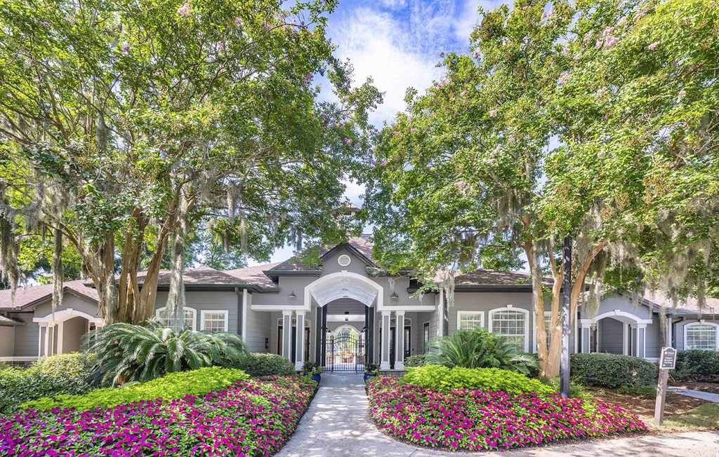 a house with trees and flowers in front of it