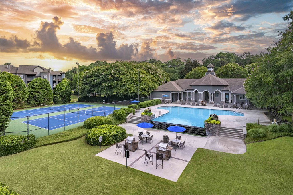 an aerial view of a backyard with a pool and tennis court