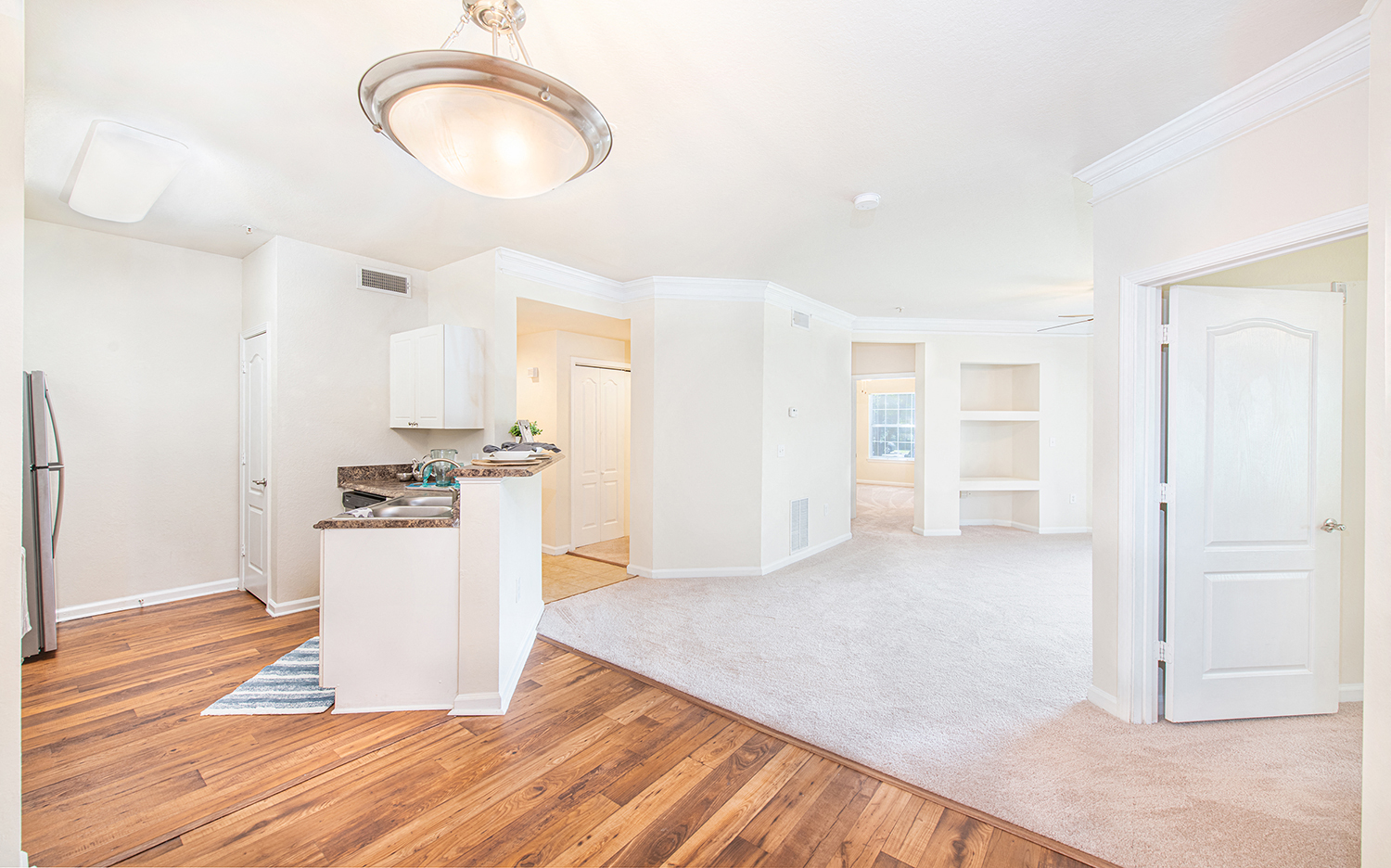 a renovated living room and kitchen with white walls and wood floors