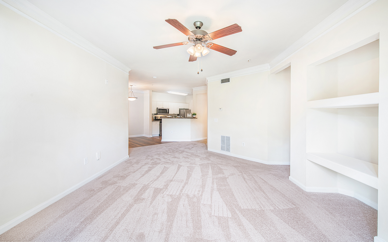a living room with white walls and a ceiling fan