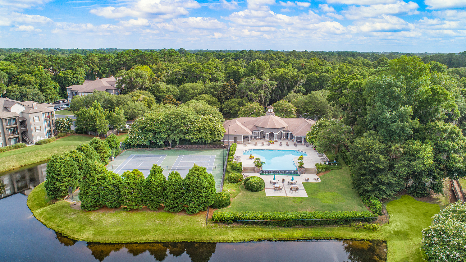an aerial view of the resort with a pool and tennis court