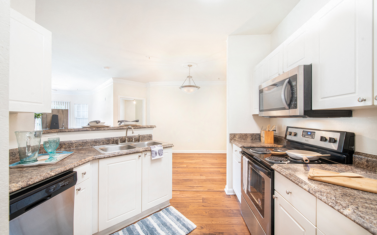 a renovated kitchen with white cabinets and granite counter tops and stainless steel appliances