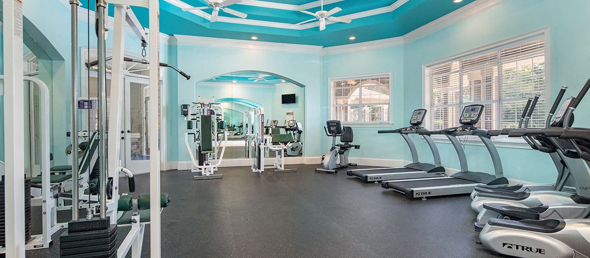 a gym with cardio equipment and weights in a room with blue walls