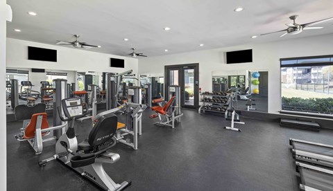 A gym with a variety of equipment including treadmills, stationary bikes, and weight machines.