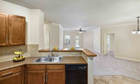 A kitchen with wooden cabinets and a black dishwasher.