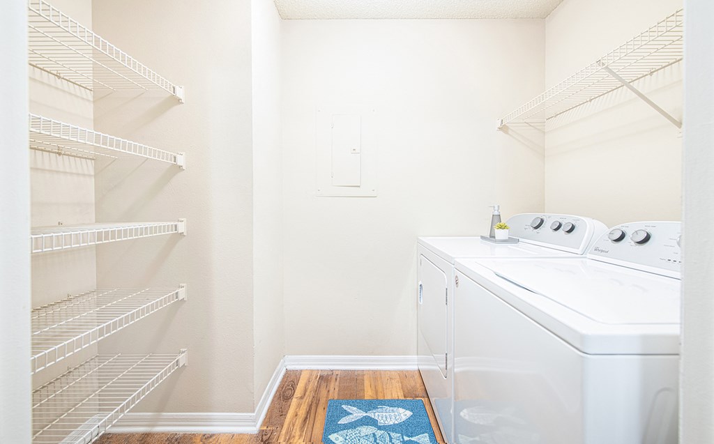 a small laundry room with a washer and dryer and a closet with shelves