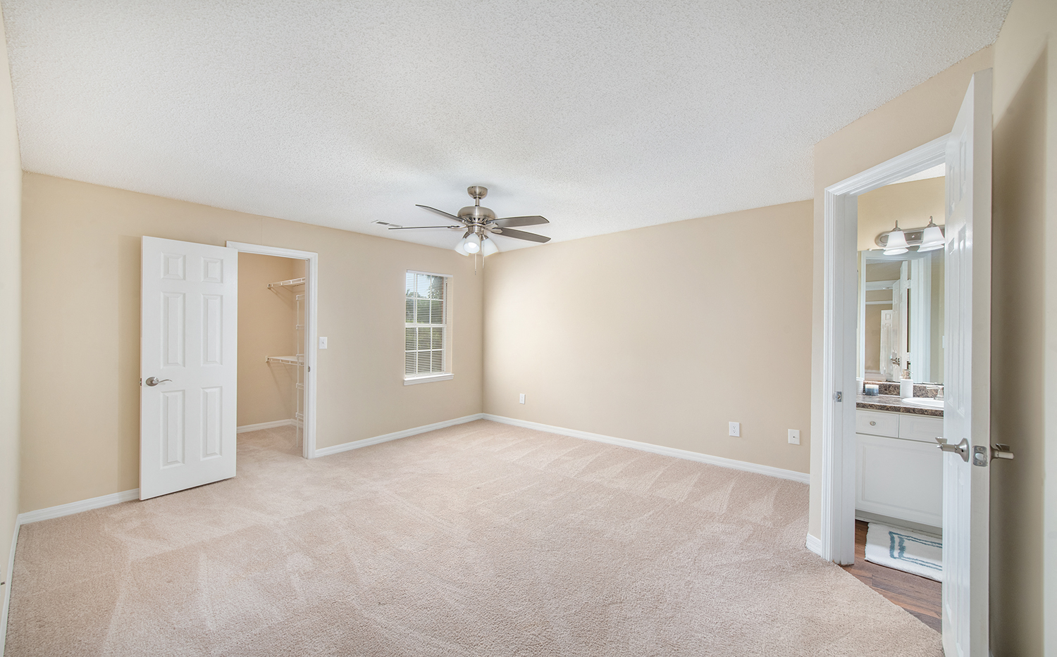 an empty living room with a ceiling fan and a closet