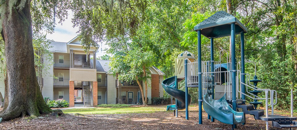 a playground with a swing set and slides in front of some apartments