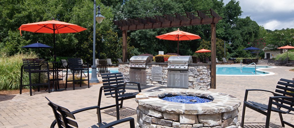a patio with a fire pit and chairs and umbrellas