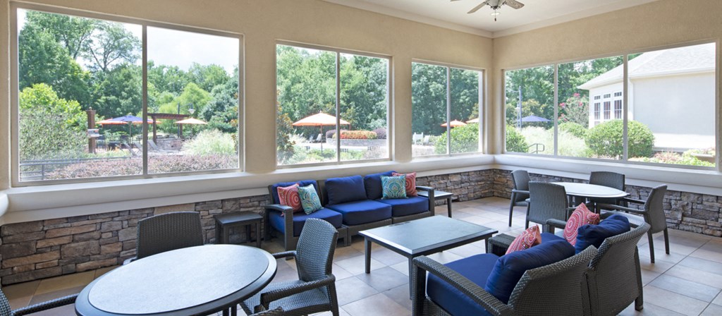 a patio with couches tables and chairs and large windows
