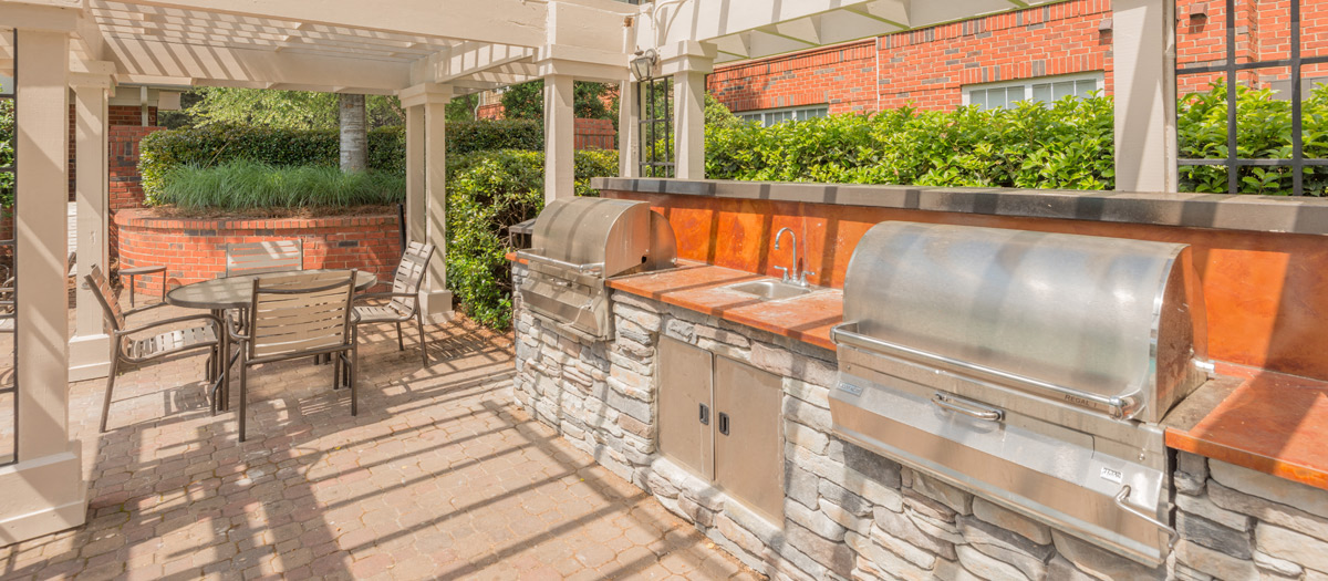 a patio with a barbecue grill and a table with chairs