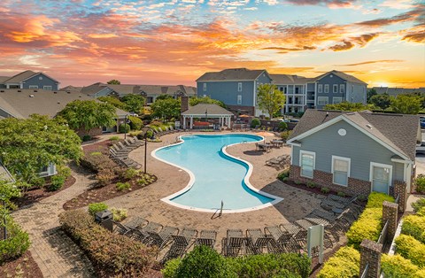 an aerial view of a swimming pool with chairs at sunset