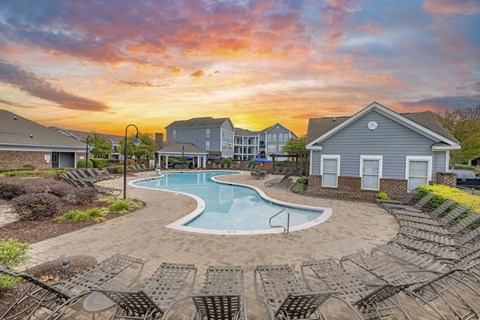 A swimming pool surrounded by lounge chairs in a residential area.