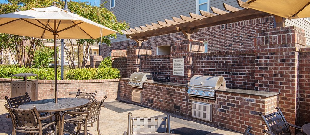 a patio with a barbecue grill and a table with chairs