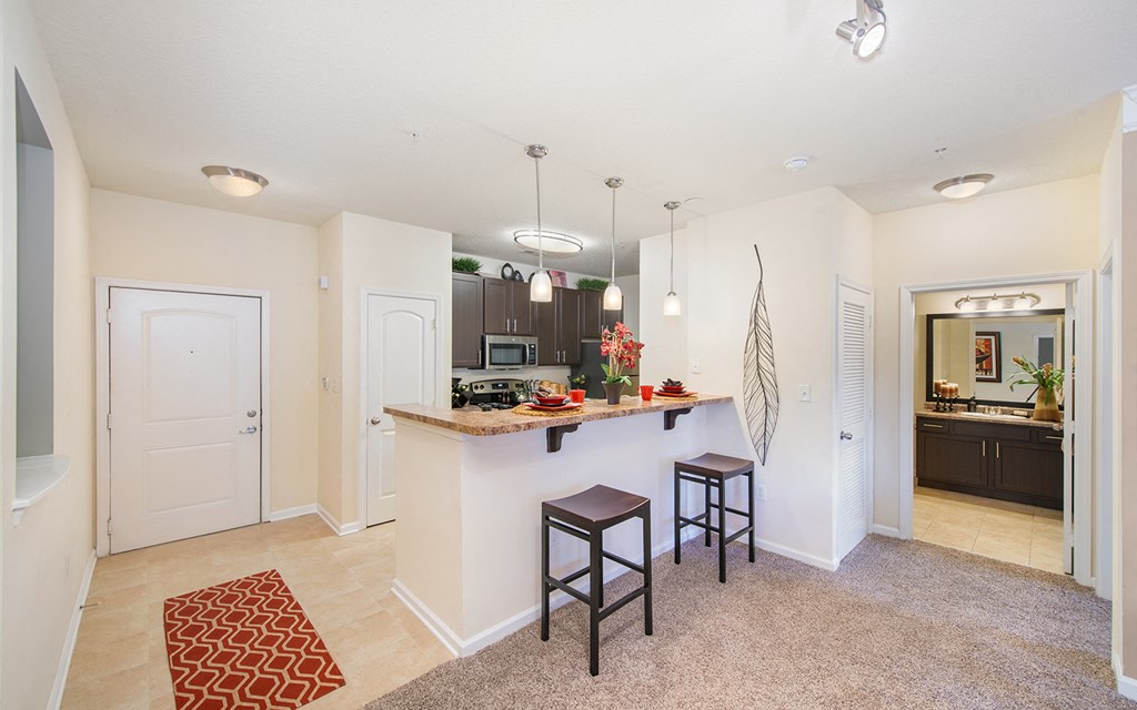 an open kitchen and living room with a bar and stools