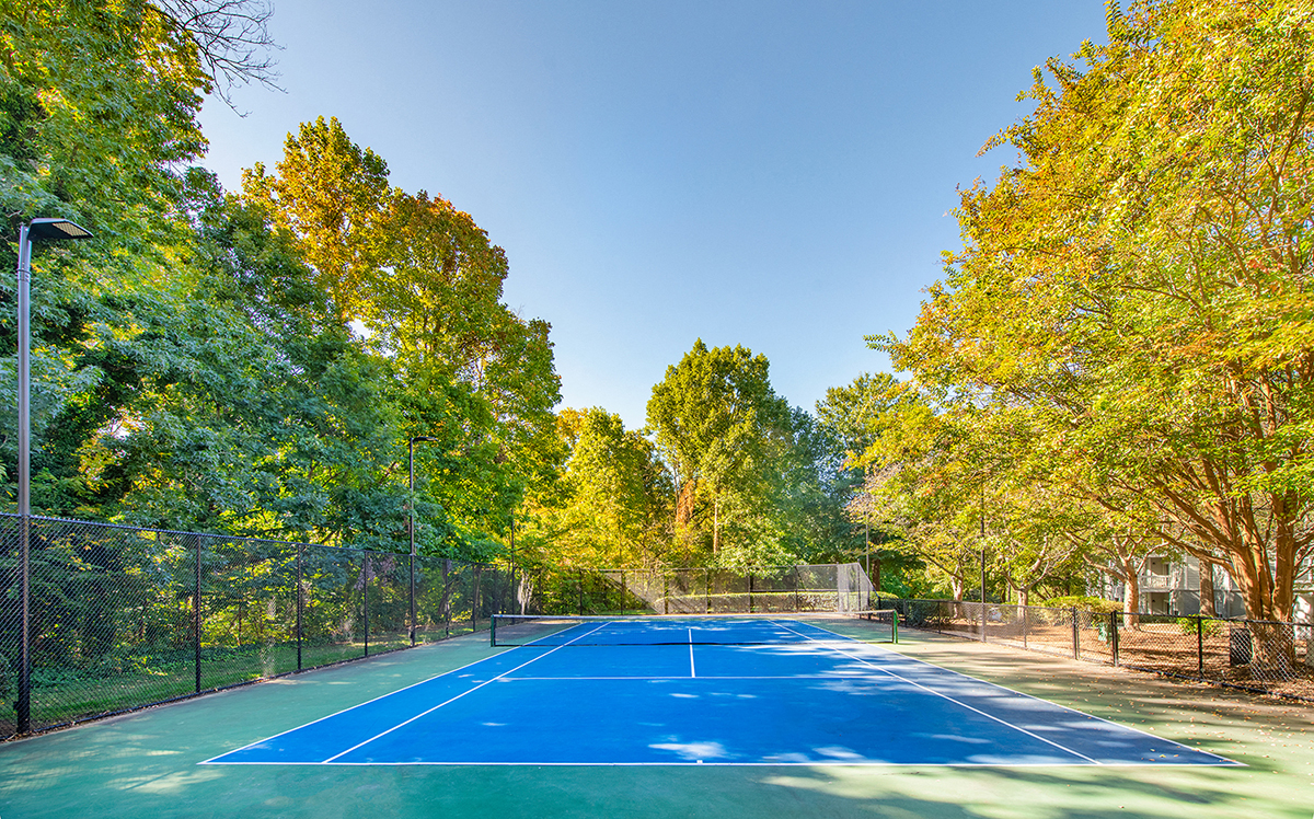 a tennis court with trees and a fence around it