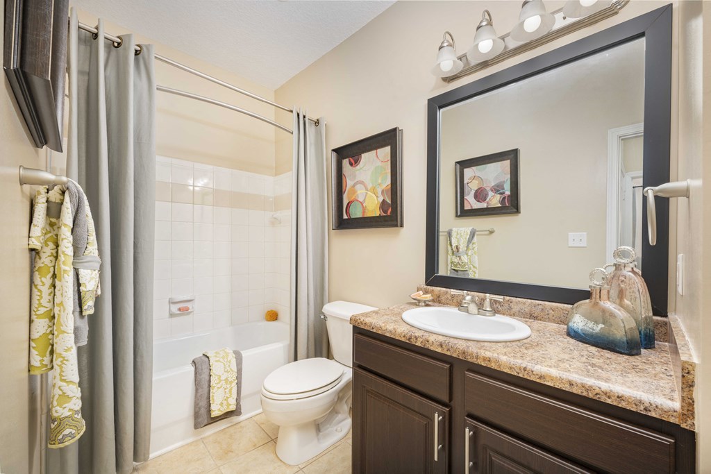 A bathroom with a toilet, sink, and mirror.