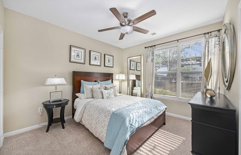 A bedroom with a bed, nightstand, and a ceiling fan.