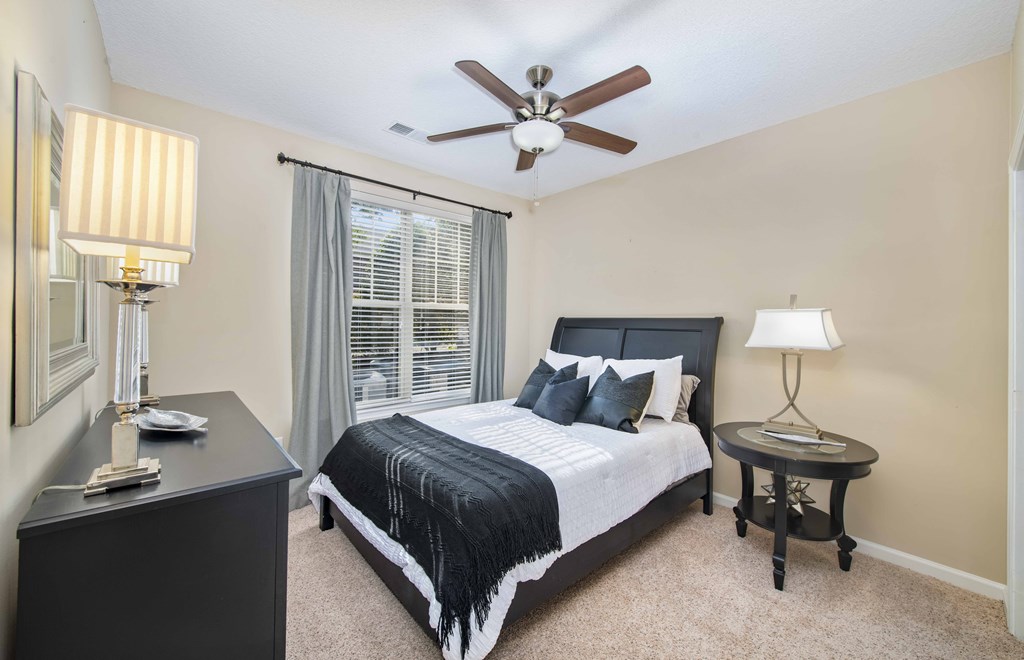 A bedroom with a bed, nightstand, and a ceiling fan.