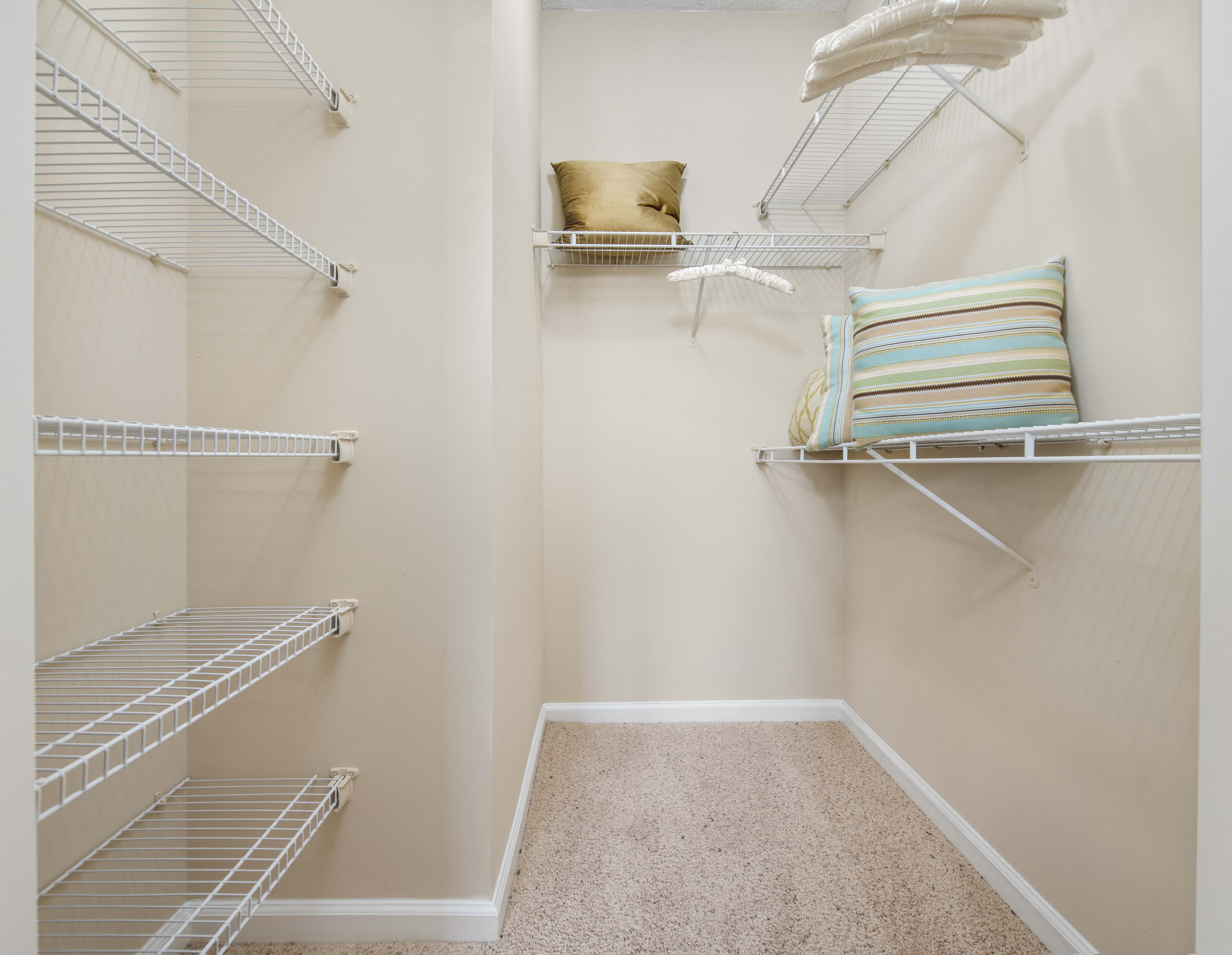 a spacious walk in closet with shelves and a chair