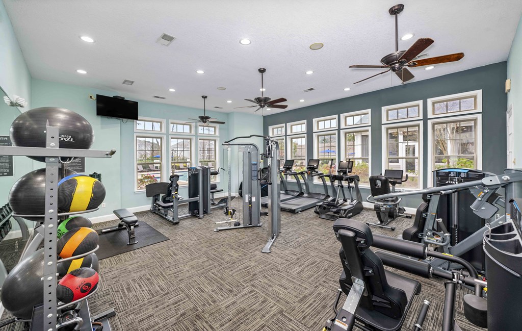 A gym with a variety of equipment including treadmills, weights, and exercise machines.