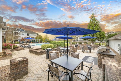A patio with tables and chairs and umbrellas.