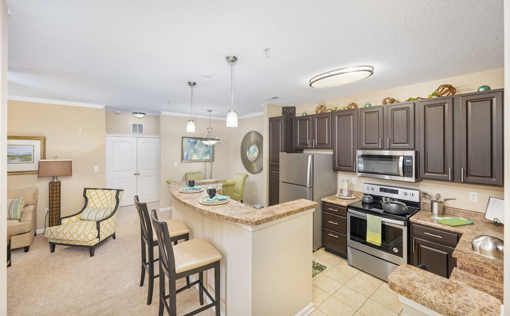A kitchen with a refrigerator, oven, and sink.