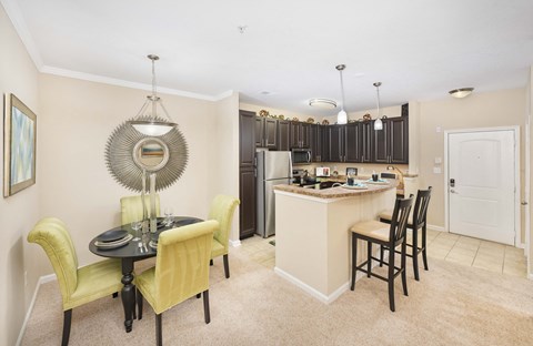 A kitchen with a table and chairs in the foreground and a counter with cabinets in the background.