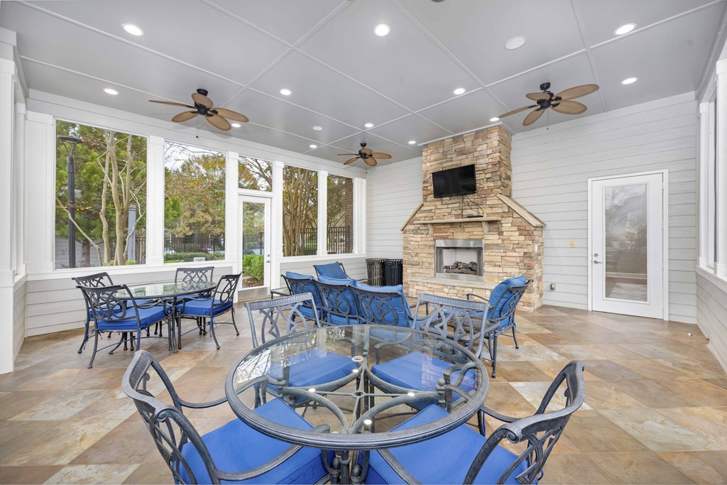 A blue table surrounded by chairs is in the middle of a room with a stone fireplace.