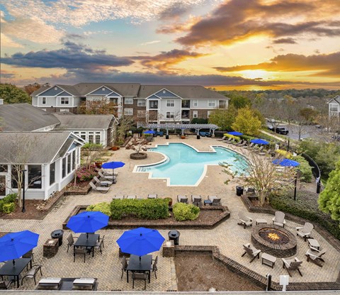 A sunset view of a pool area with a fire pit and lounge chairs.