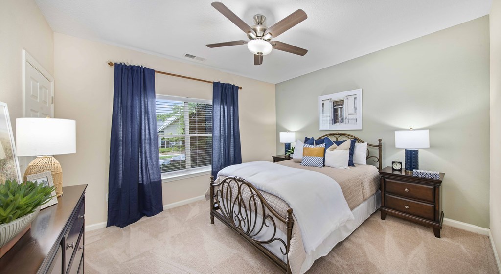 A bedroom with a bed, nightstand, and a ceiling fan.