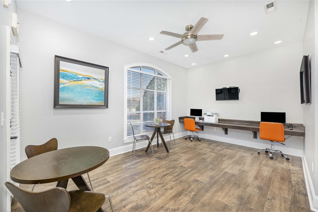 A room with a table, chairs, and a painting on the wall.