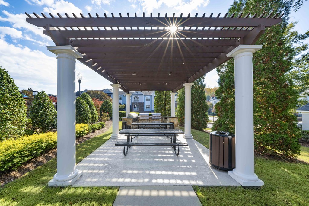 A white pergola with a bench underneath it.