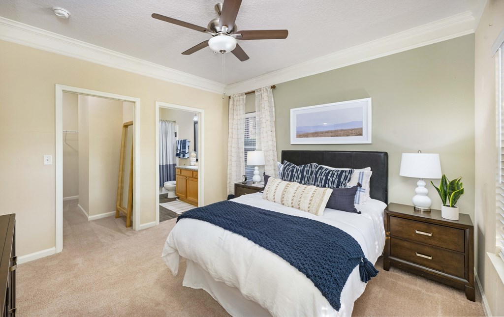 A bedroom with a bed, nightstand, and a ceiling fan.