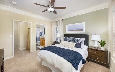 A bedroom with a bed, nightstand, and a ceiling fan.