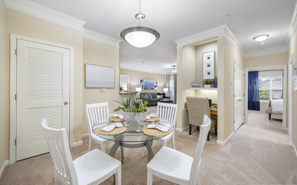 A dining room with a glass table and white chairs.
