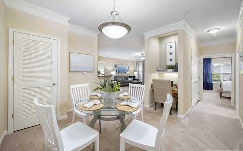A dining room with a glass table and white chairs.