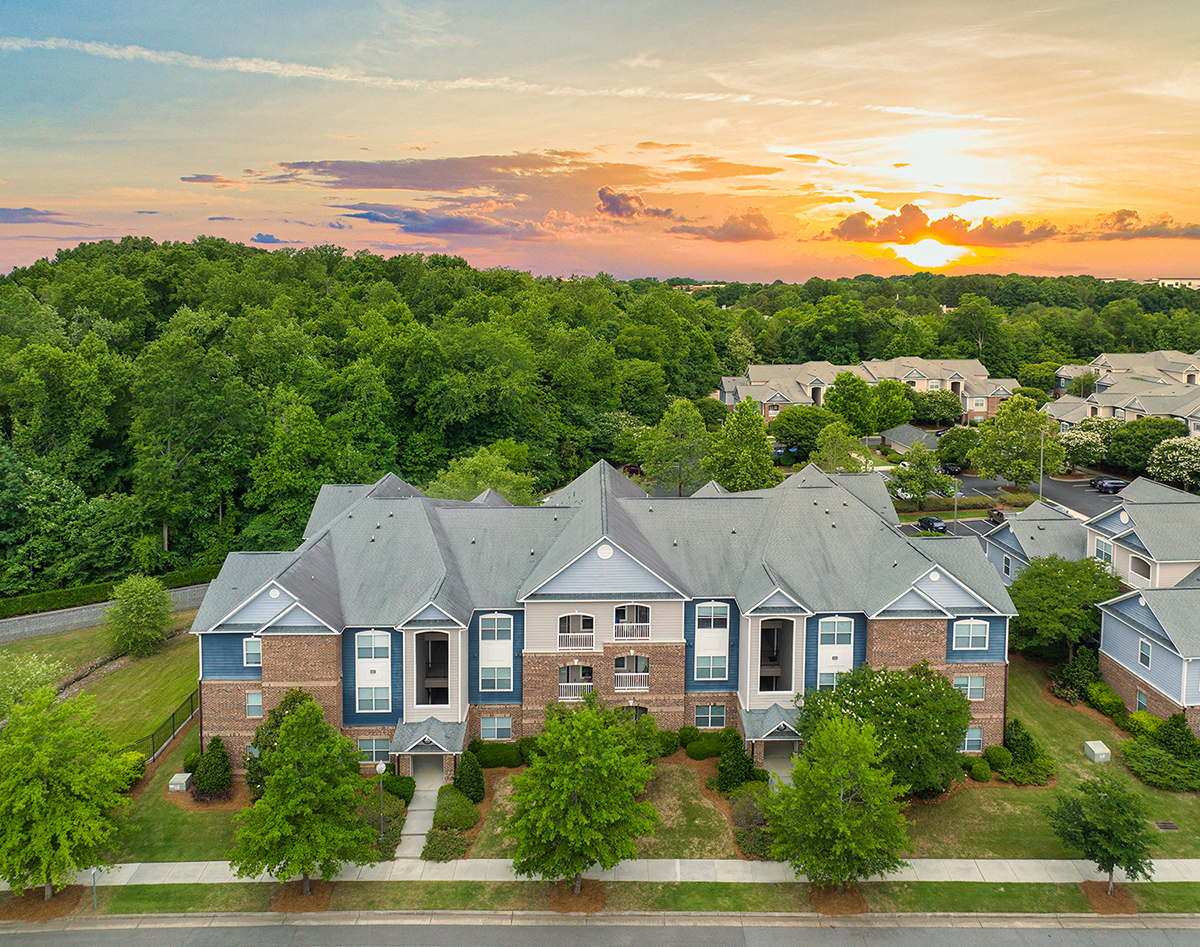an aerial view of a row of houses with a sunset in the background