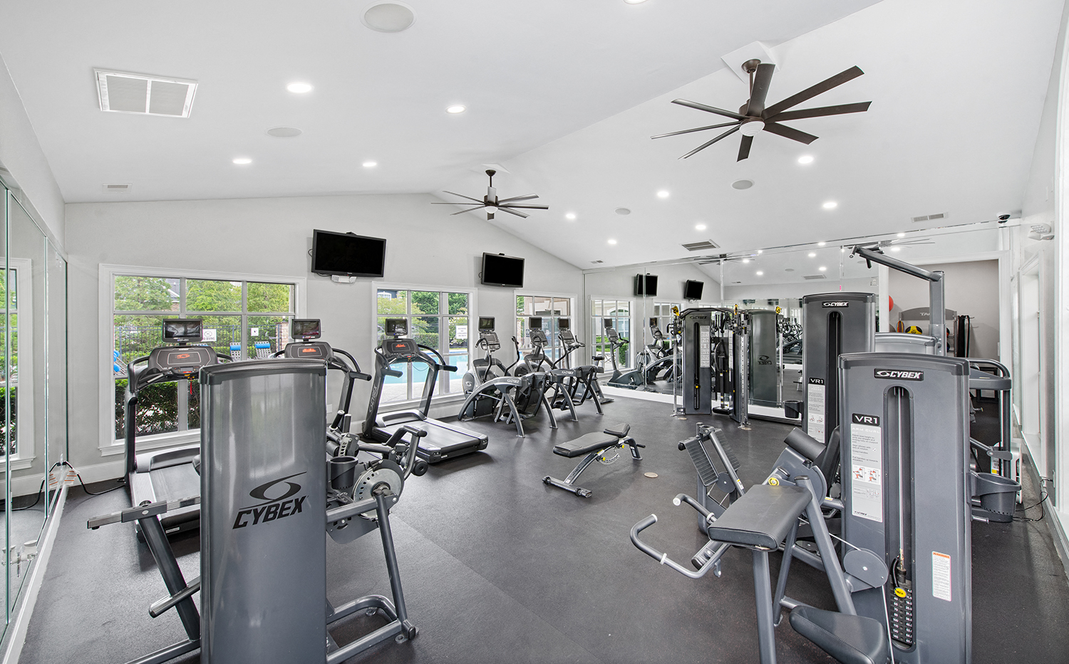 a gym with cardio equipment and ceiling fans