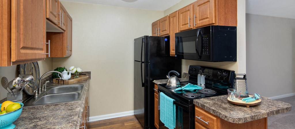 a kitchen with black appliances and granite counter tops and wooden cabinets