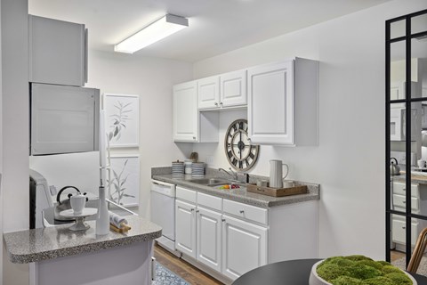 A modern kitchen with white cabinets and a granite countertop.