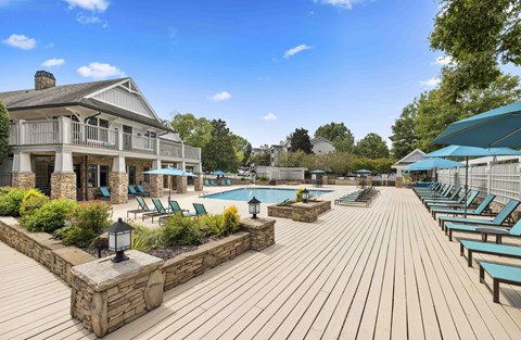 A wooden deck with a pool and lounge chairs.